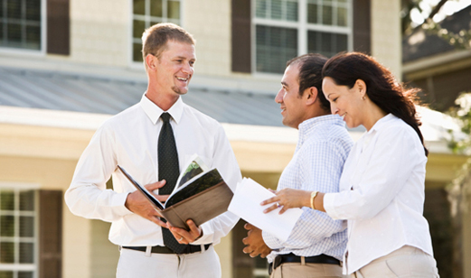 Real estate agent showing brochure of house to Hispanic couple looking for new home